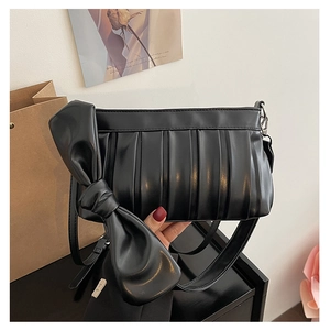 Dettaglio della borsa a tracolla nera increspata con fiocco decorativo e clip in metallo