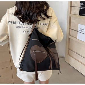 Detail of canvas tote bag showing side-view on model with brown leather heart pockets