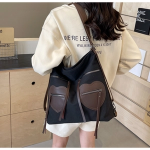 Detail of canvas tote bag featuring dual brown heart-shaped pockets and wide shoulder straps