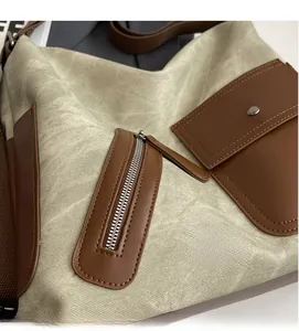 Detail view of green canvas shoulder bag with brown leather pockets and silver zippers