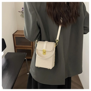 Chic beige woven crossbody phone bag with gold clasp shown on model in a cozy interior