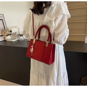 Detail of red bridal handbag with floral embroidery, woven handle and Double Happiness charm