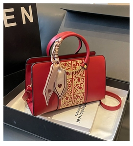 Close-up of red wedding handbag with golden floral embroidery in a black premium gift box