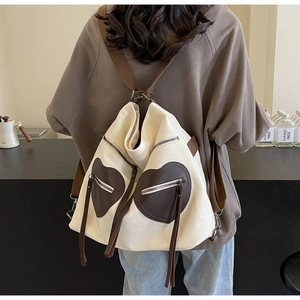 Detail of off-white canvas backpack featuring two brown heart-shaped zipper pockets