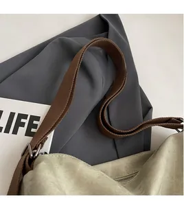 Detail of adjustable brown woven shoulder strap with metal buckle on canvas backpack