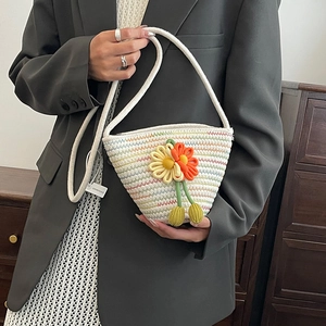 Handwoven straw bucket bag with floral accents for summer beach beach vacation styling