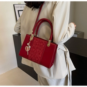 Detail of red wedding handbag with embossed floral patterns and heart pearl charm