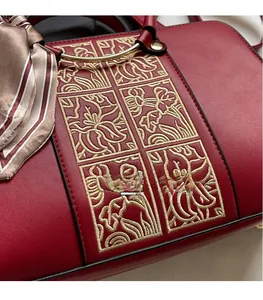 Detail of red wedding handbag with floral embroidery and silk scarf on gold handle