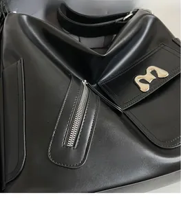 Detailansicht aus glattem schwarzem Leder mit silbernem M-Logo und Reißverschluss-Detail