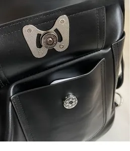 Detail der schwarzen Leder-Tasche mit silberner Schmetterling-Platte und Magnetverschluss