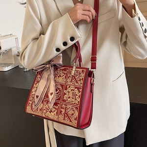 Elegant red leather bridal handbag with gold floral embroidery and silk ribbon detail