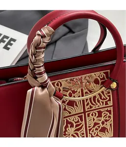 Detail of red leather bridal bag with gold embroidery and silk scarf handle