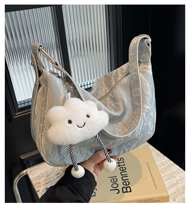Detail of silver metallic pleated hobo bag with a cute cloud plush charm and wavy texture