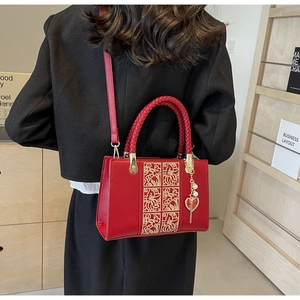Detail of red wedding handbag with golden floral embroidery and pearl heart charm