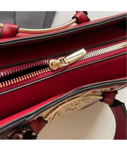 Detail of red leather bridal handbag featuring gold zipper puller and elegant patterns