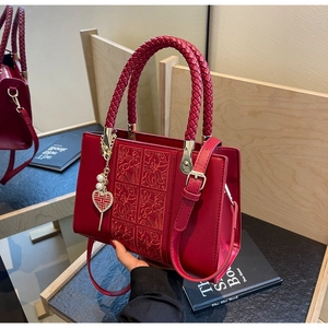 Detail of red wedding handbag with floral embroidery and gold Xi heart pendant