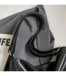 Detail eines glänzenden schwarzen Leder-Schultergurts mit silberner Metallschnalle