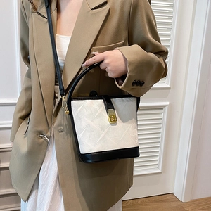 Chic monochrome bucket bag with quilted texture and gold lock shown on shoulder