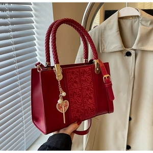 Detail of red wedding handbag featuring floral embroidery and a golden Double Happiness charm