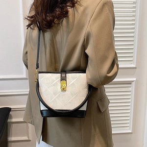 White bucket bag with geometric texture, black leather trim, and gold hardware on model