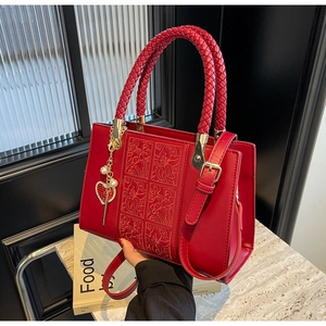 Detail of red bridal leather bag with floral embossing and pearl heart charm accessory