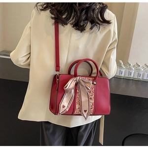 Detail of red bridal handbag with gold embroidery and heart silk scarf on model