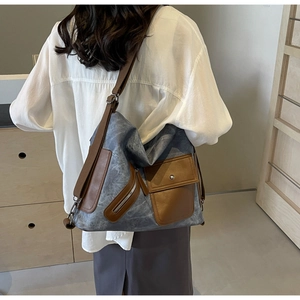 Detail of blue canvas tote bag featuring brown leather trim and adjustable shoulder strap