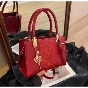 Detailed embroidery and woven handle of red bridal handbag with lucky charm