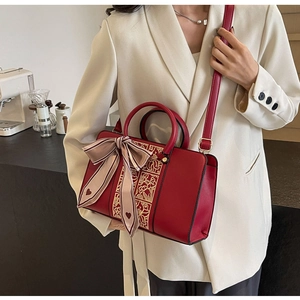 Detail view of red bridal handbag with golden flower embroidery and silk ribbon bow accent