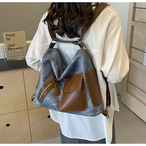 Detail of grey canvas tote with brown leather straps and metal zipper pockets