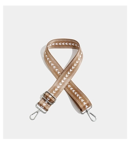 Macro detail of brown wide strap with white V-pattern and silver metal buckle