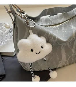 Detail of creative white cloud plush pendant with striped legs on a gray shoulder bag