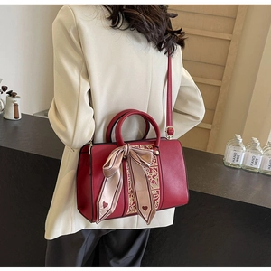 Detail view of burgundy handbag with floral embroidery and silk bow on white suit