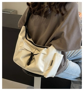 Detail of off-white canvas tote bag with multi-pocket design and black rope accents