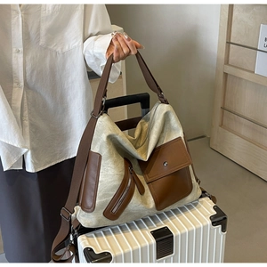 Detail of canvas and leather tote bag resting on a white suitcase in a minimal interior