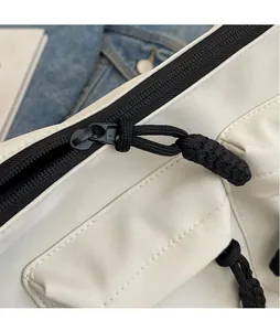 Detail of sleek black metal zipper pull and woven cord on a white canvas tote bag