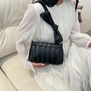 Borsa a tracolla chic in pelle nera plissettata con maxi fiocco indossata da modella