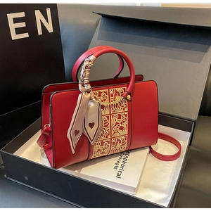 Detail of red wedding handbag with gold embroidery and decorative heart silk scarf