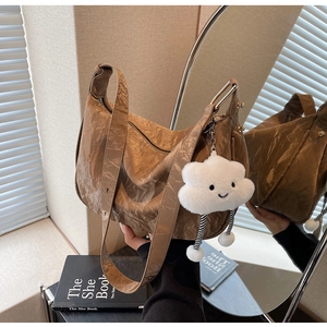 Macro shot of brown pleated texture handbag with soft cloud plush charm and wide strap