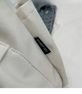 Detailed close-up of cream white canvas tote bag with a woven brand tag and fine stitching