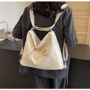 Detail eines cremefarbenen Lederrucksacks mit M-Metalllogo und mehreren Reißverschlüssen