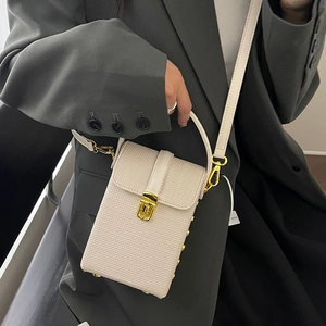 Creamy white crossbody phone bag with grid texture and golden lock on grey suit