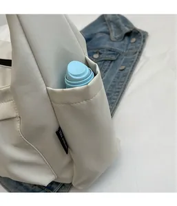 Detail of a beige canvas tote side pocket holding a blue water bottle for storage