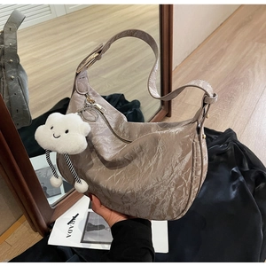 Detail of light gray crinkled patent leather hobo bag with a plush cloud charm