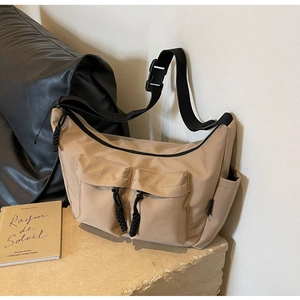 Detail of beige canvas messenger bag with large cargo pockets and adjustable wide black strap