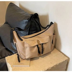 Detail of khaki canvas tote bag showing front flap pockets and adjustable black strap