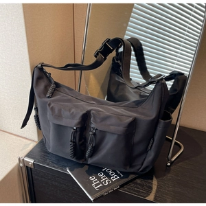 Detail of durable black nylon crossbody bag with dual utility pockets and tactical buckle