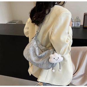 Silver metallic pleated dumpling bag with white cloud plush charm in a detailed macro view