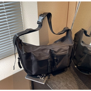 Detail of black utility messenger bag featuring multi-pockets and woven zipper pulls