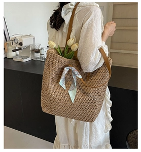 Detail of woven straw tote bag with brown leather straps and blue floral silk scarf
